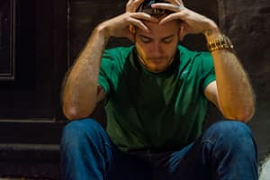 Hombre sentado con la cabeza en las manos experimentando síntomas de abstinencia de alcohol