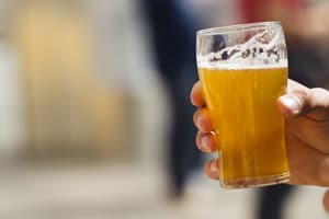 Mano sosteniendo una porción de cerveza en vaso