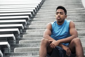 muscular male youth sits on bleacher steps