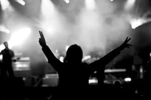 Music and Drugs silhouette of woman at concert holding hands up in the air
