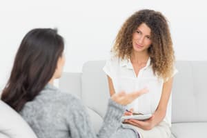 Good Rehab Therapy Session two women sitting on couch and chair portraying a therapist and patient during rehab therapy session