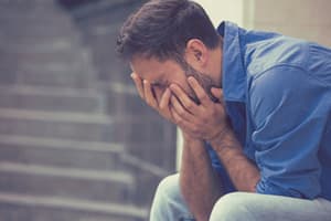 Librium Withdrawal Effects man sitting on step holding face portraying an individual experiencing withdrawal effects of Librium