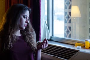Young woman holding acamprosate pill thinking about rehab