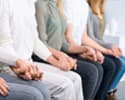 Sitting group of addicts hold hands in rehab program